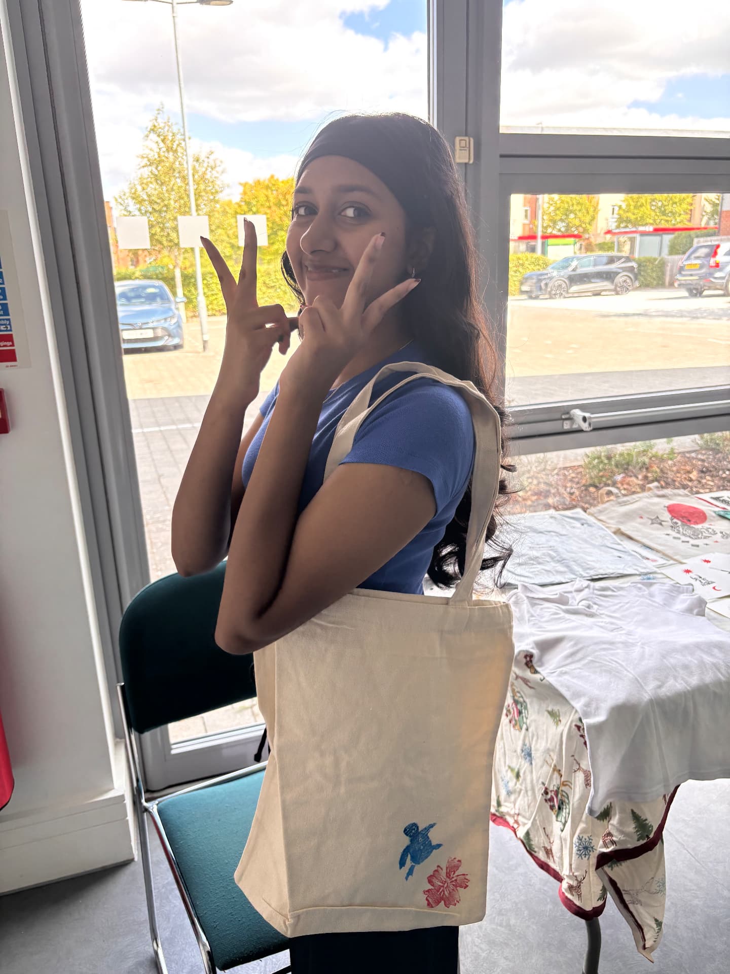 A workshop guest holding up her printed tote bag with her hands raised in celebration