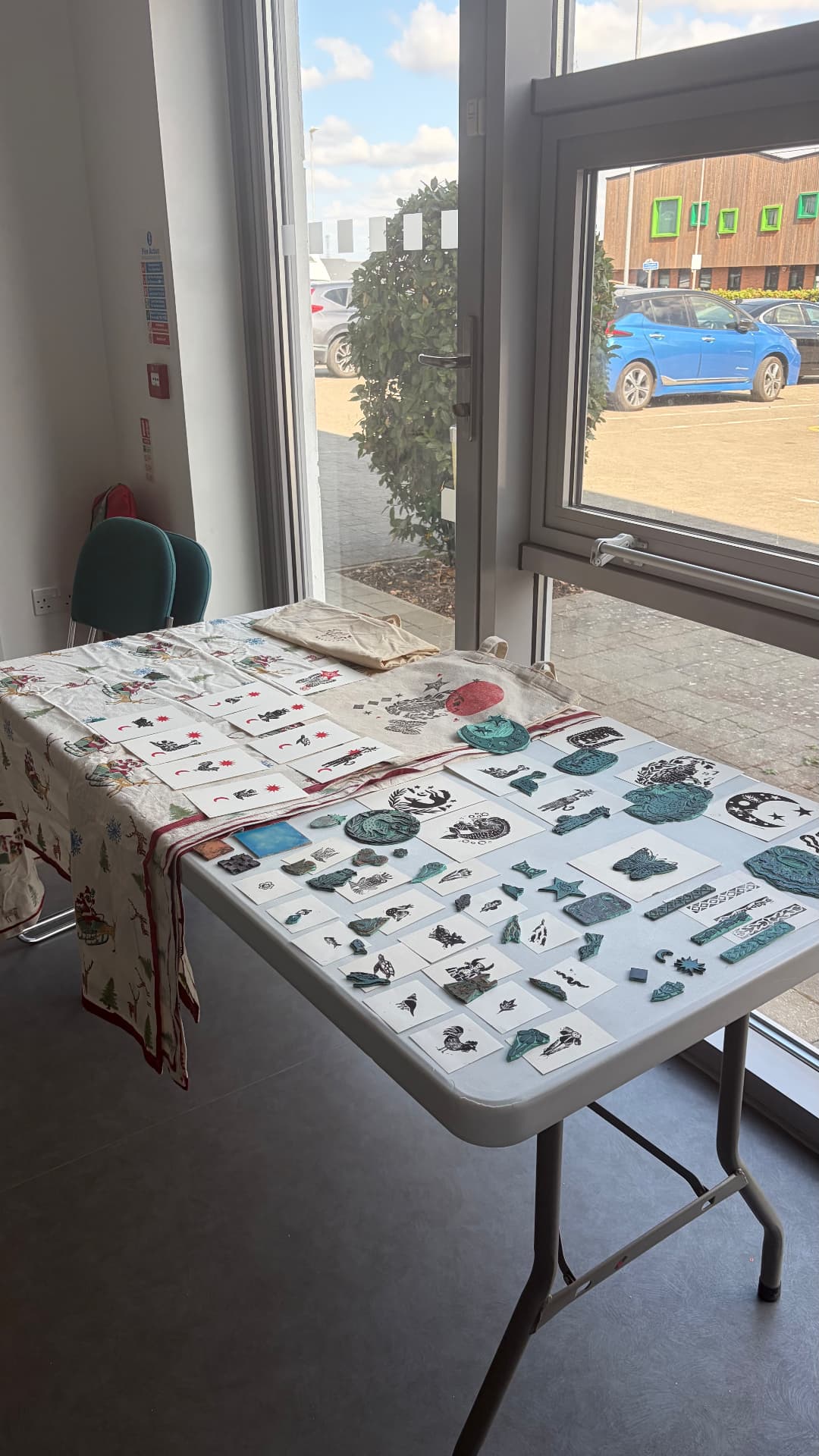 A table covered in freshly printed lino prints drying by the window
