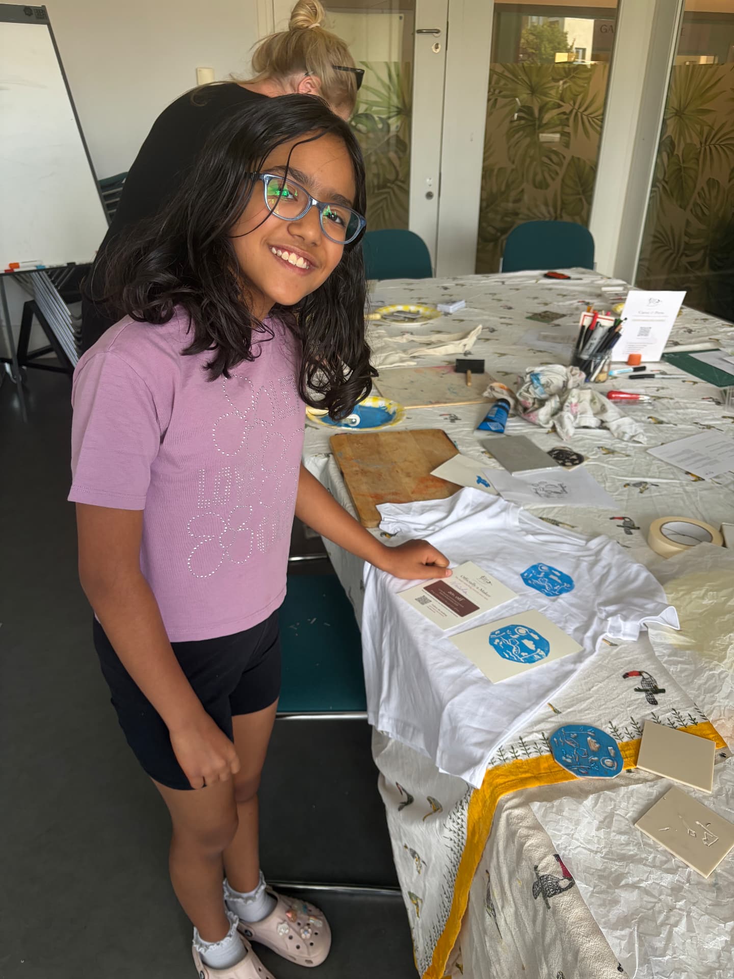 A smiling girl beside the table with her hand-printed t-shirt