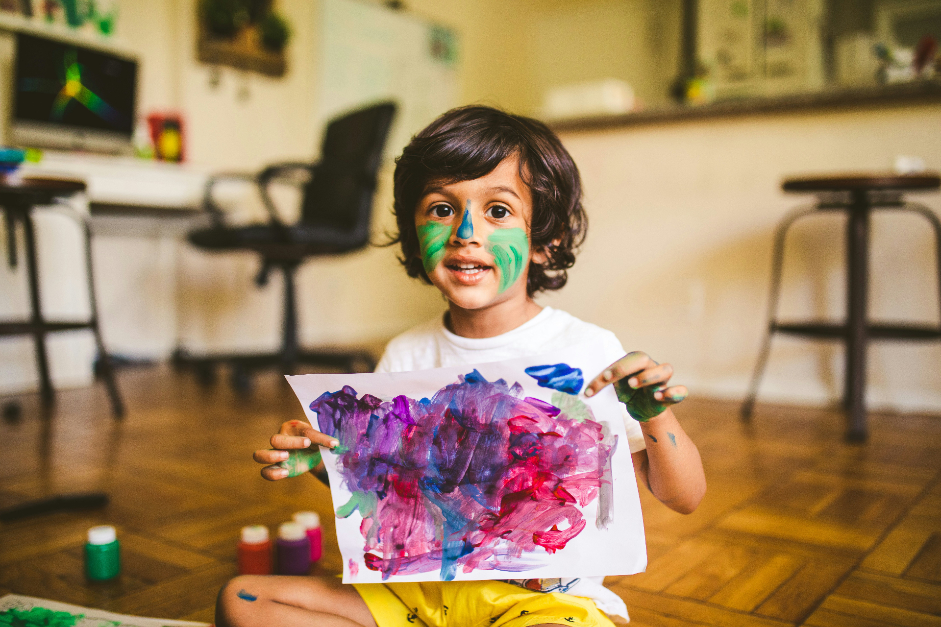 Child smiling, holding a hand-drawn picture
